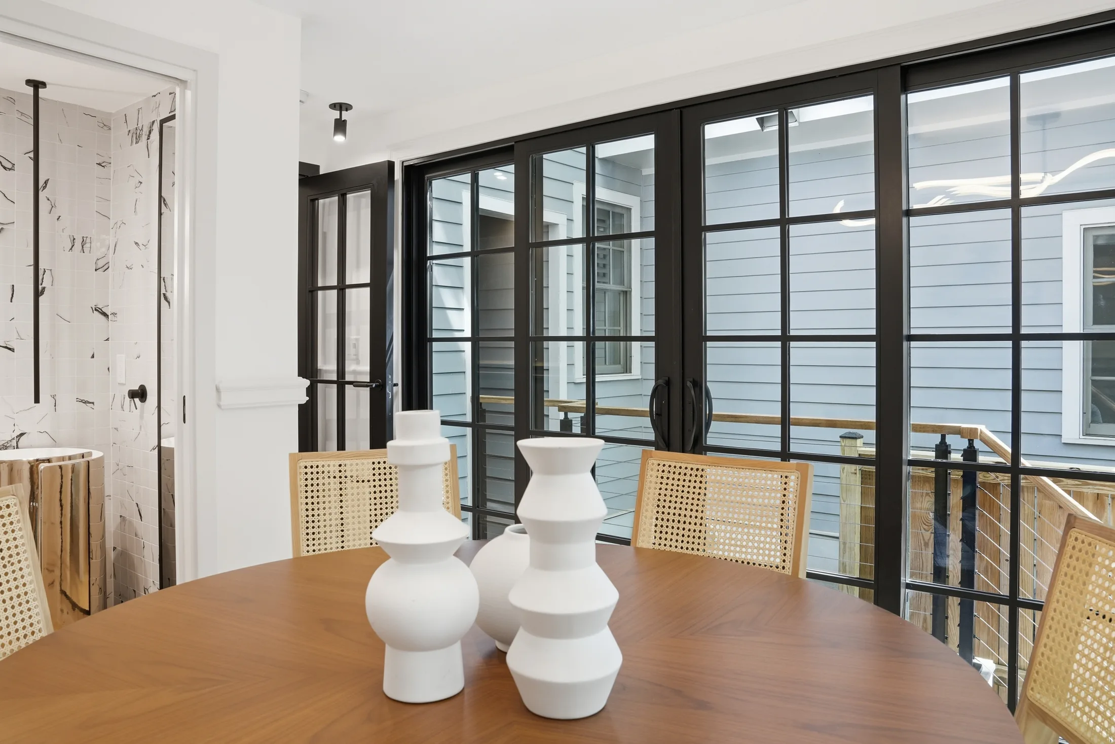 Round walnut dining table before steel-framed doors at Casa Ulivo